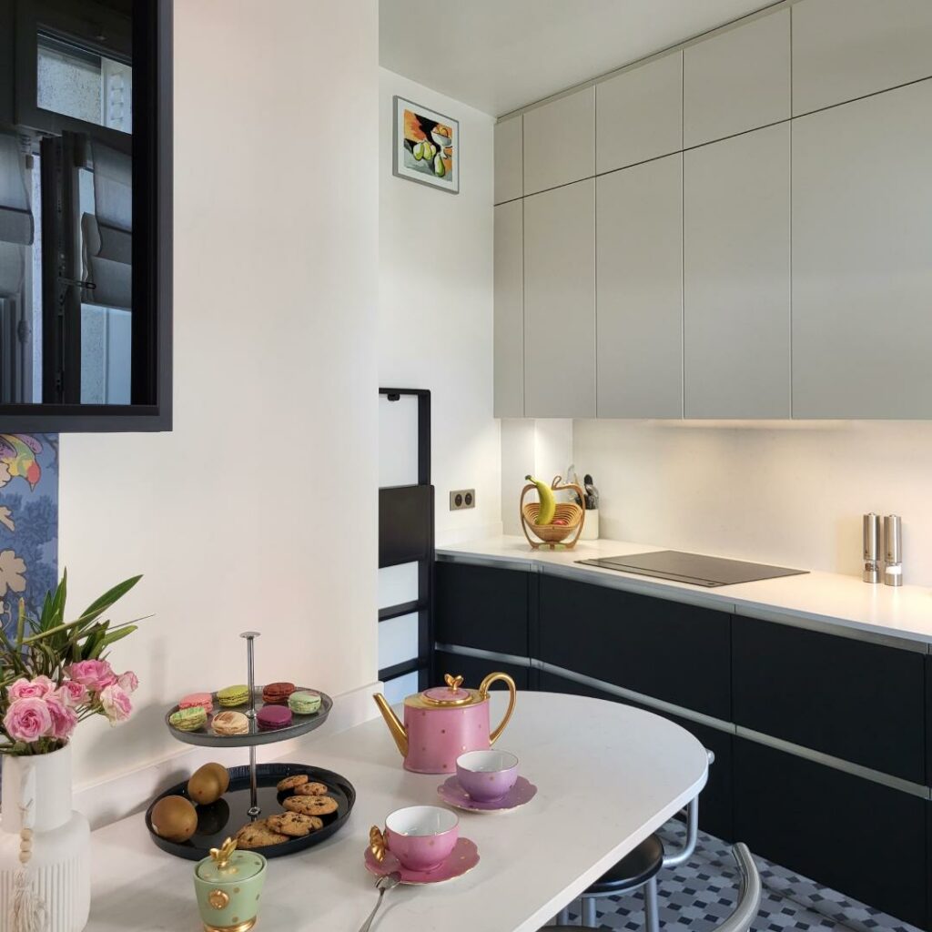 Cuisine moderne avec meubles hauts beige et noirs, plan de travail intégré et coin repas, ambiance design et fonctionnelle, projet d’architecture intérieure