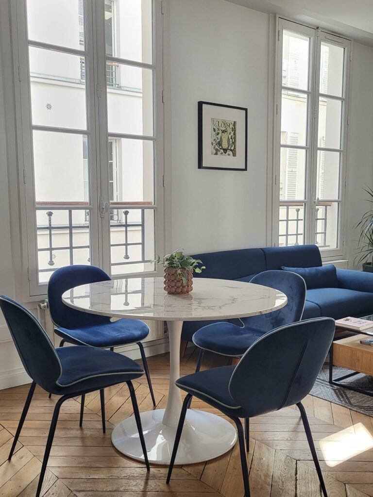Table ronde tulipe en marbre avec 4 chaises en velours bleu.